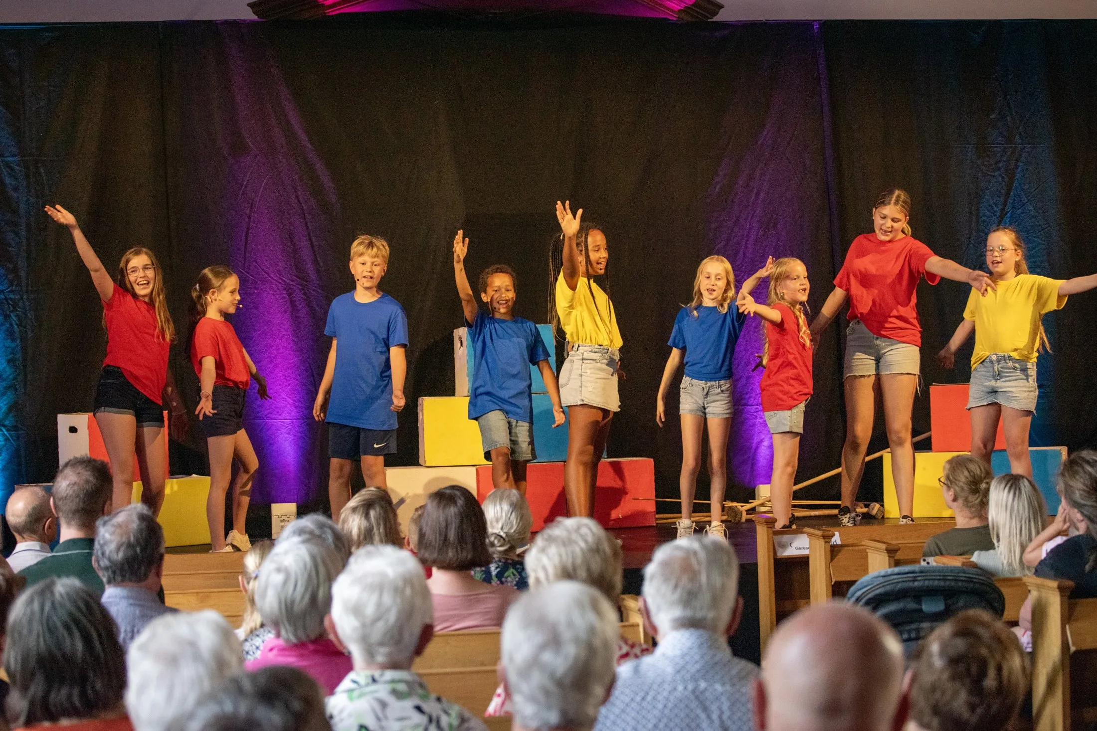 De kids zingen en zwaaien naar het publiek