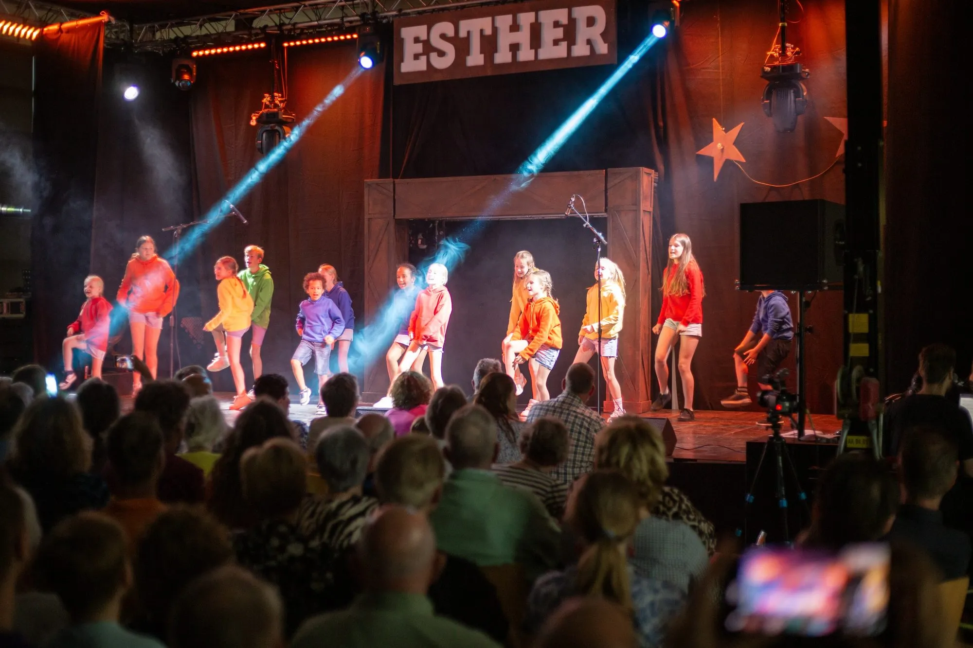 Lichtbundels door de rook boven kinderen op het podium van Esther